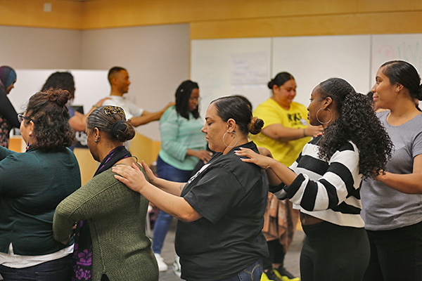 A group of women grabbing their shoulders in a circle