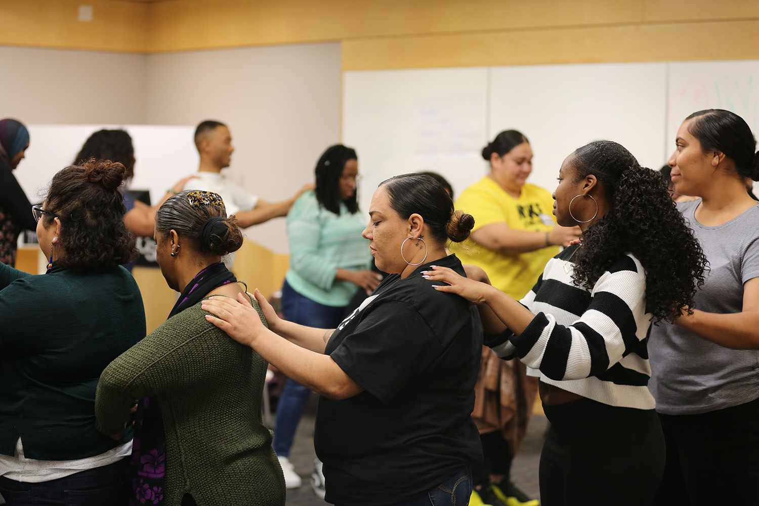 A group of women grabbing their shoulders in a circle